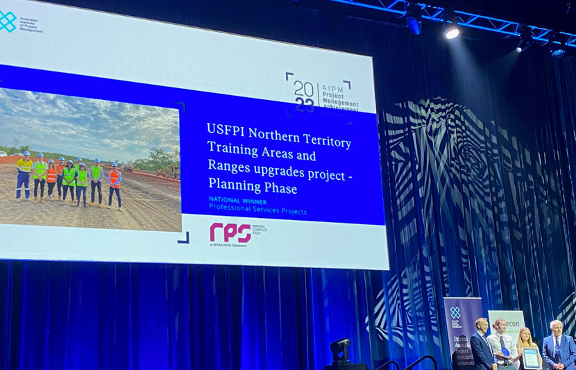 RPS award recipients on stage with a slide behind them that explains, RPS was recognised for its outstanding management of the Planning Phase of the USFPI NT Training Areas and Ranges project.