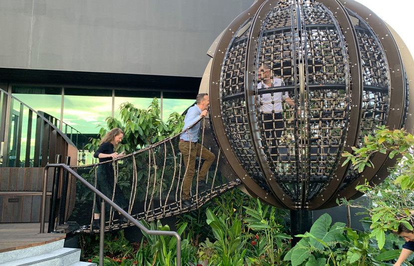 RPS landscape architects walk over a draw bridge which leads to a hanging dome over a lush garden.  